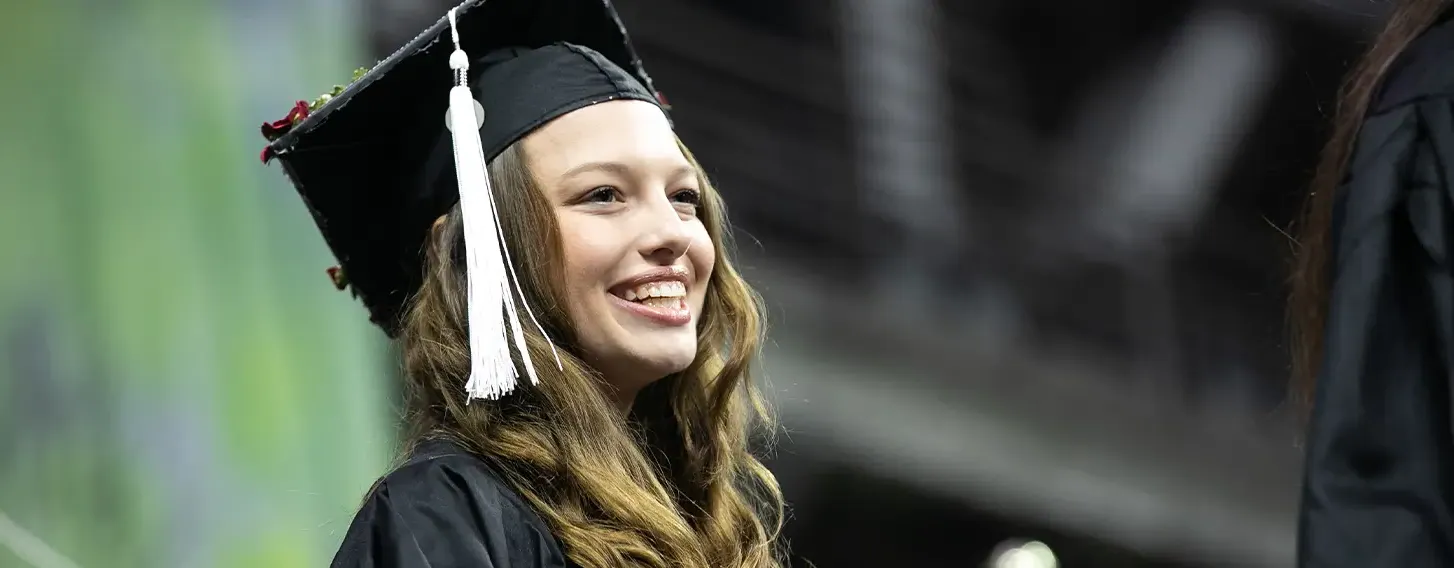 A smiling girl in a graduation gown and cap.